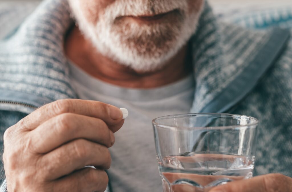 senior man takes pill with glass of water in hand 2024 04 10 16 59 34 utc
